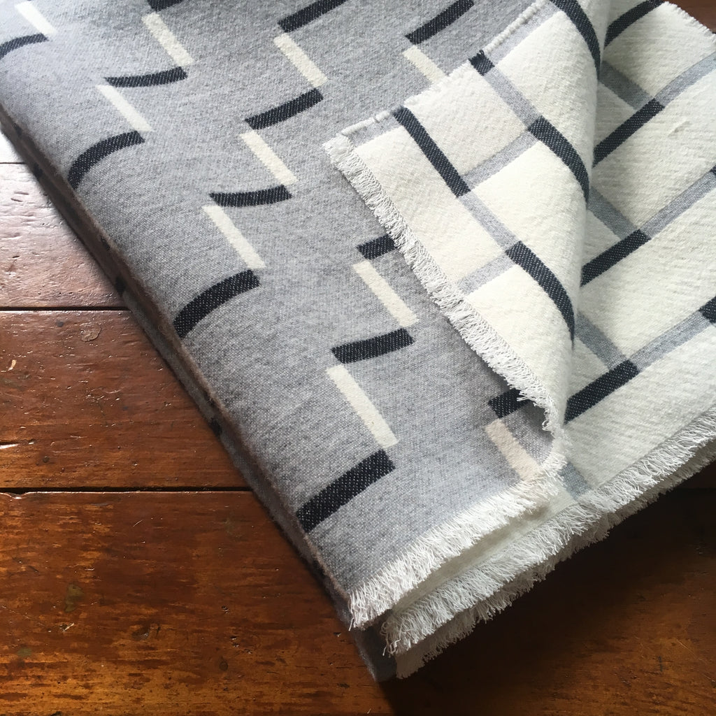 Contemporary, grey, merino wool blanket. Geometric, monochrome design. Woven in England.